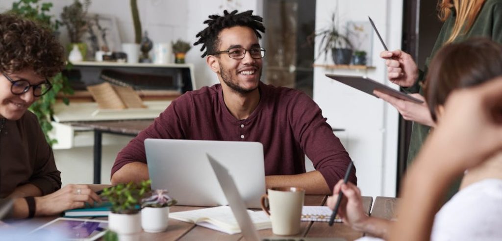 QSE entreprise : Groupe de jeunes professionnels en réunion de travail dans un environnement de bureau moderne, illustrant une dynamique collaborative typique d'une démarche QSE en entreprise axée sur la qualité, la sécurité et l’environnement
