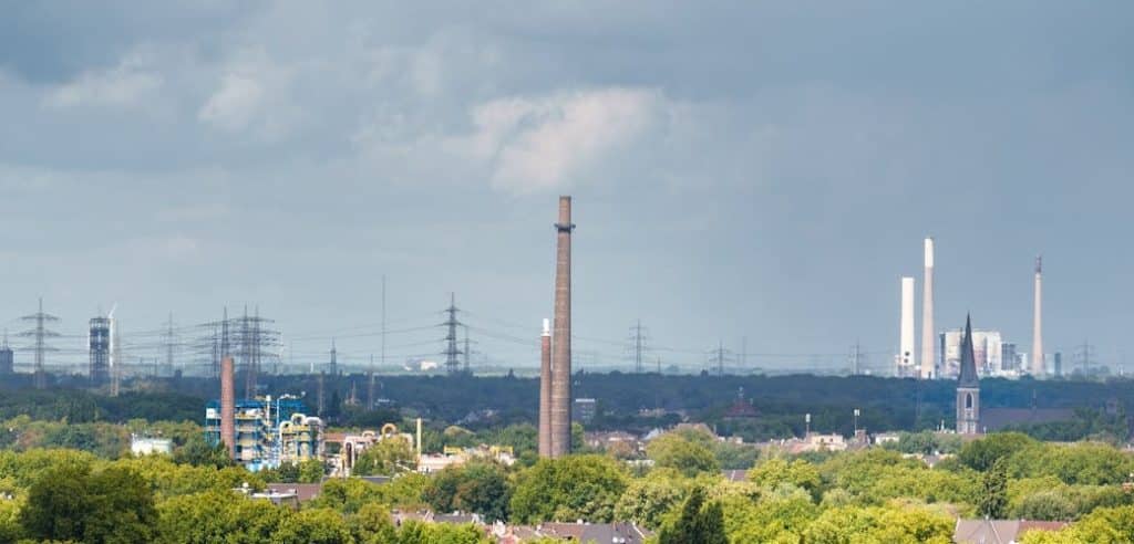 ecologie industrielle : image d'une cheminée d'usine crachant des volutes de fumée blanche